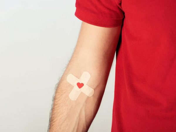 Bluttest un Blutspenden. Partial view of patient in red t-shirt with plasters on grey background. © lightfieldstudios, # 118536493 123rf.com .