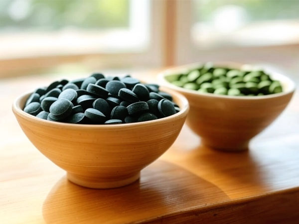 Foto: Eine Schale mit Spirulina-Presslingen und eine Schale mit Chlorella-Presslingen steht auf einem Holztisch. © foodfibel.de